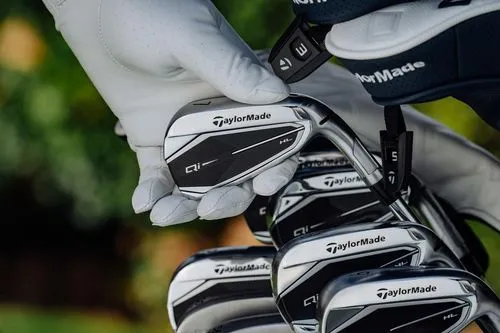 Golfer grabbing a TaylorMade Qi iron from their bag, alongside other TaylorMade clubs. 