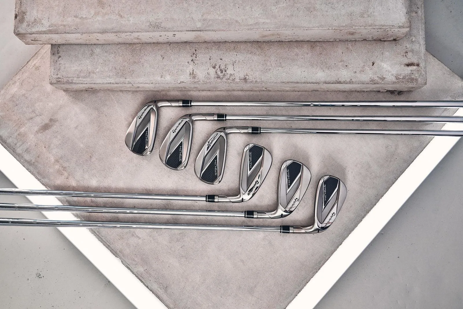 TaylorMade Stealth HD Irons with metal shafts and heads arranged neatly on concrete steps.