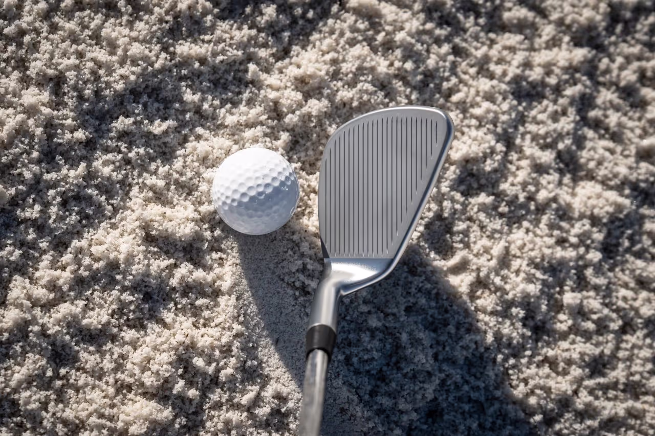 Birds-eye view of a PING BunkR Sand Wedge in the sand, positioned next to the ball.