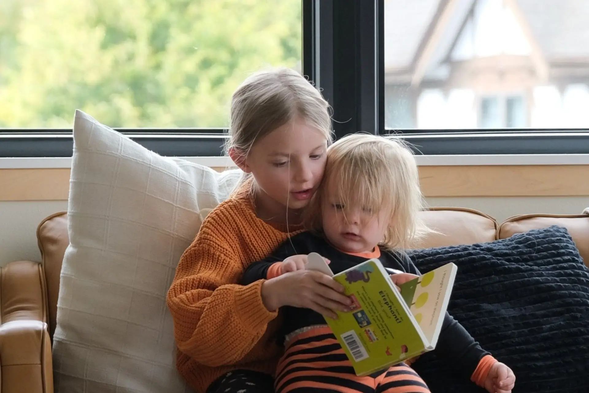 Brother and sister reading a book together while doing homeschool as a family