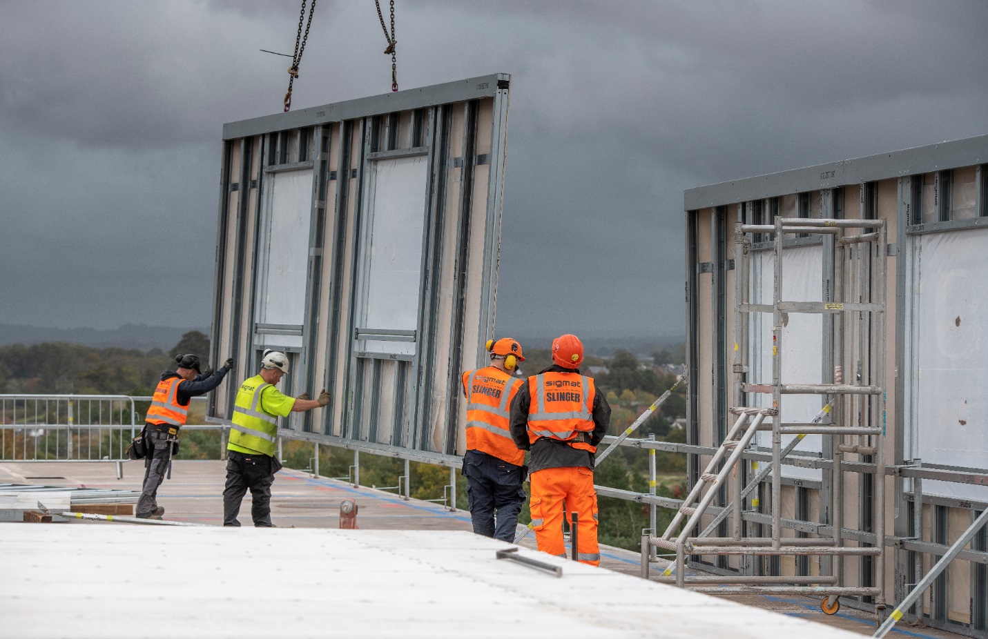 Construction workers install a modern prefabricated wall panel on a building.

