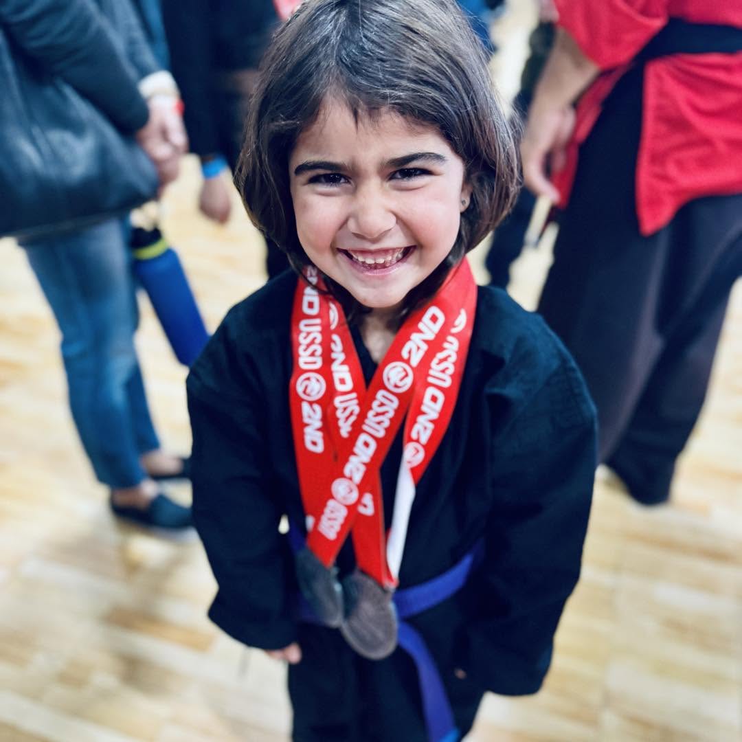 A USSD Irvine Kids Karate student at a tournament wearing their medals.