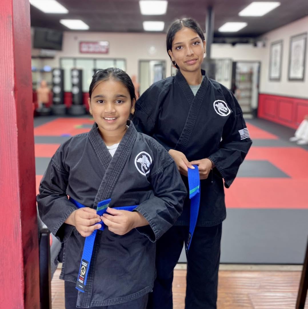 Teenage Karate students wearing a black uniform and blue belts soon after they achieved a stripe.