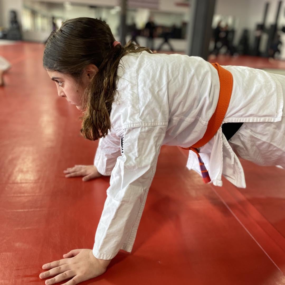 A teen Orange belt working out in a pushup for their Self Defense class.
