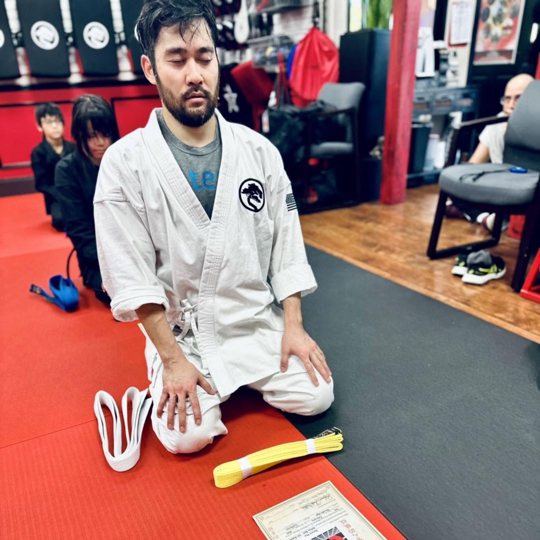 Adult Karate Student kneeling and meditating after their yellow belt test.