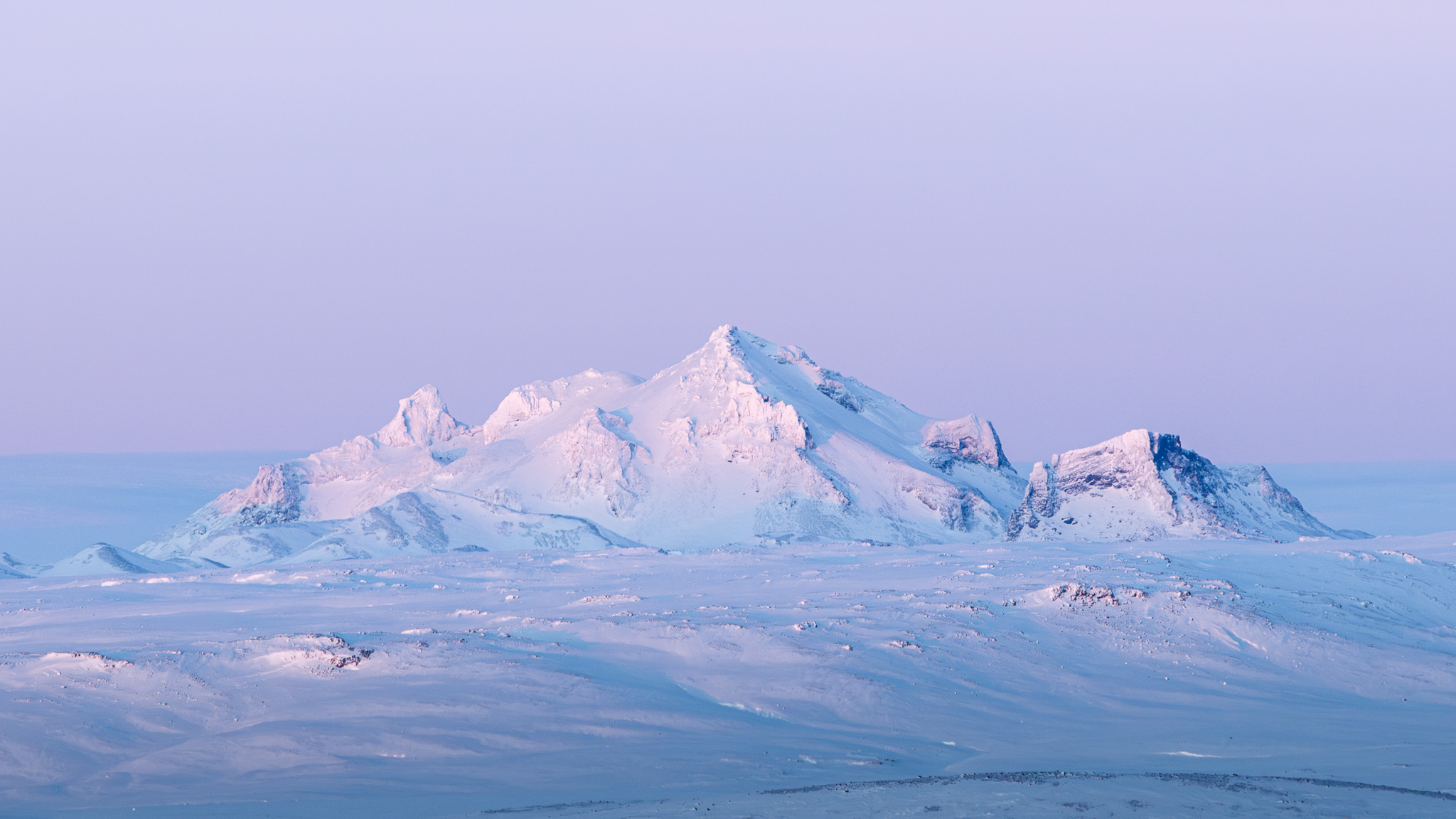 A snowy mountain with pink sky.