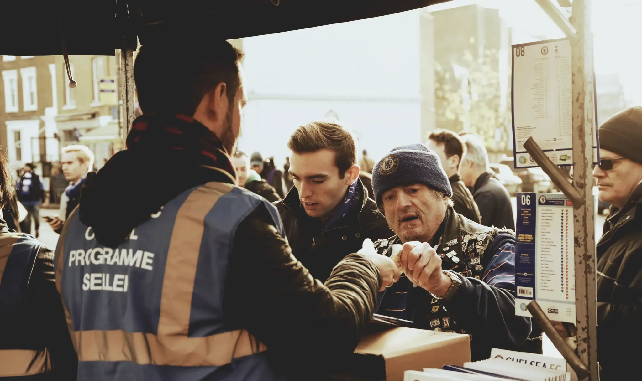 A football supporter buying a printed matchday programme outside a stadium