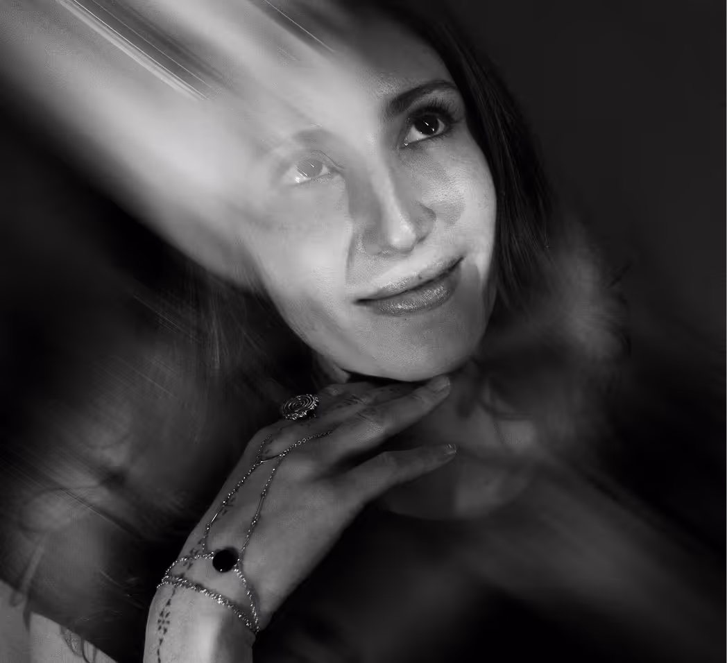 Black and white portrait of a woman with a thoughtful smile and a decorative hand chain.