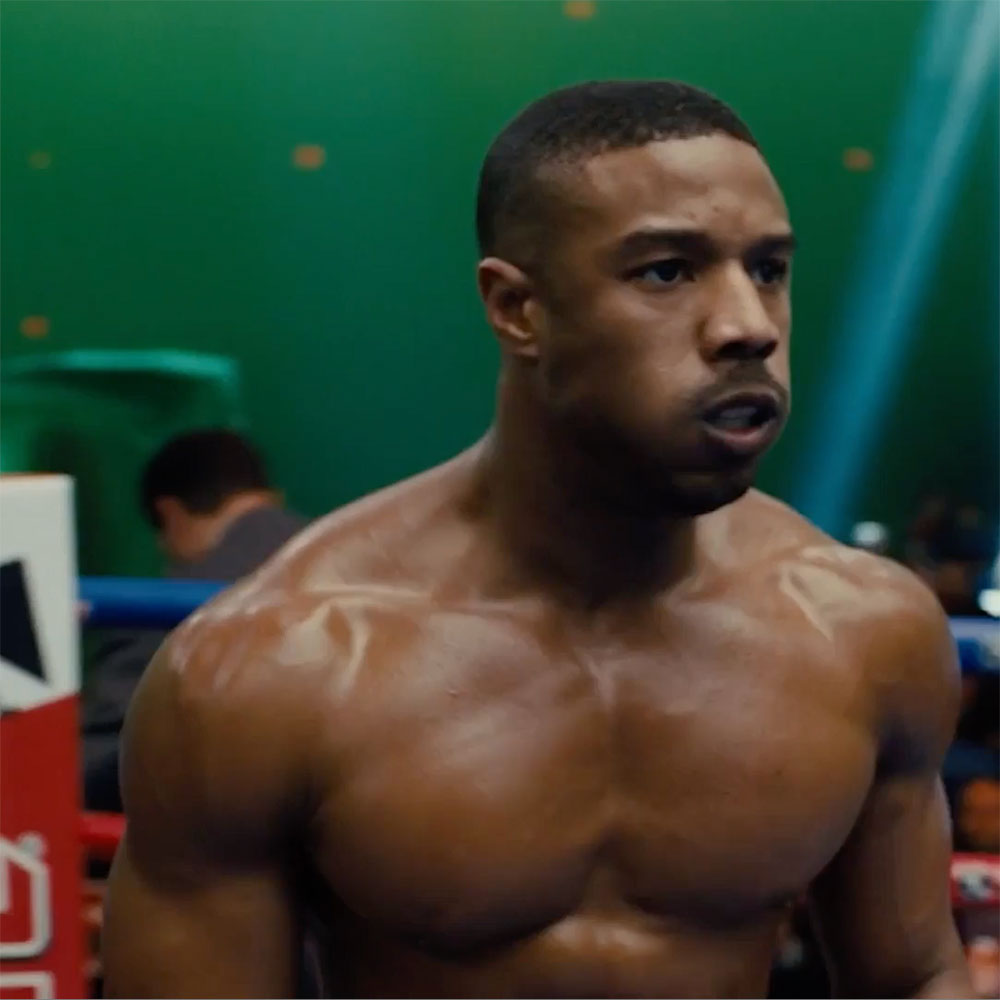 A freeze frame of the actor Michael B Jordan in the film Creed 2 standing in front of a green screen