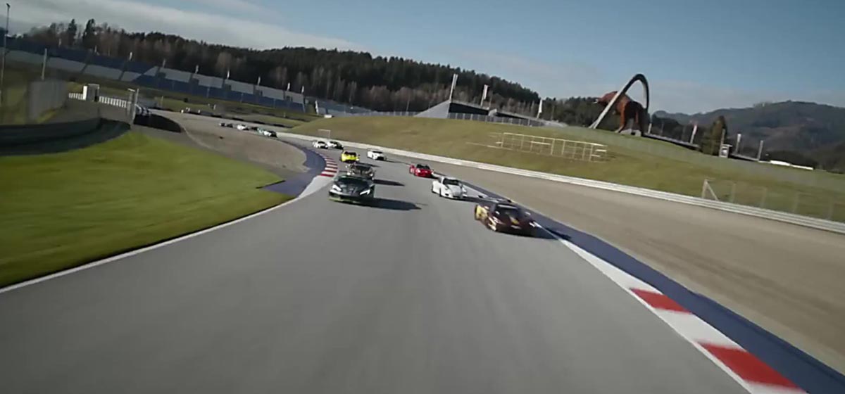 Several race cars speed towards the camera on a racing track