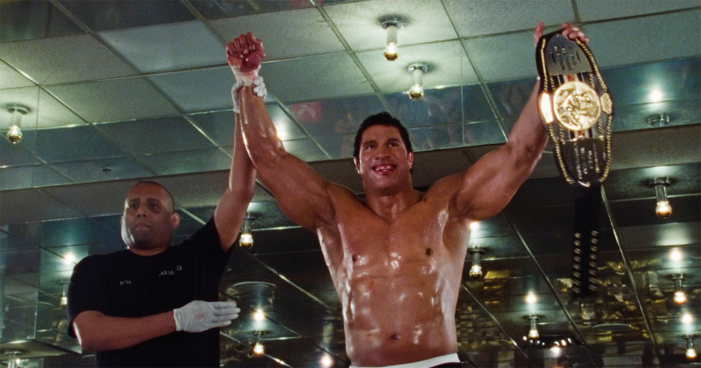 A man holds a wrestling championship belt up after a win