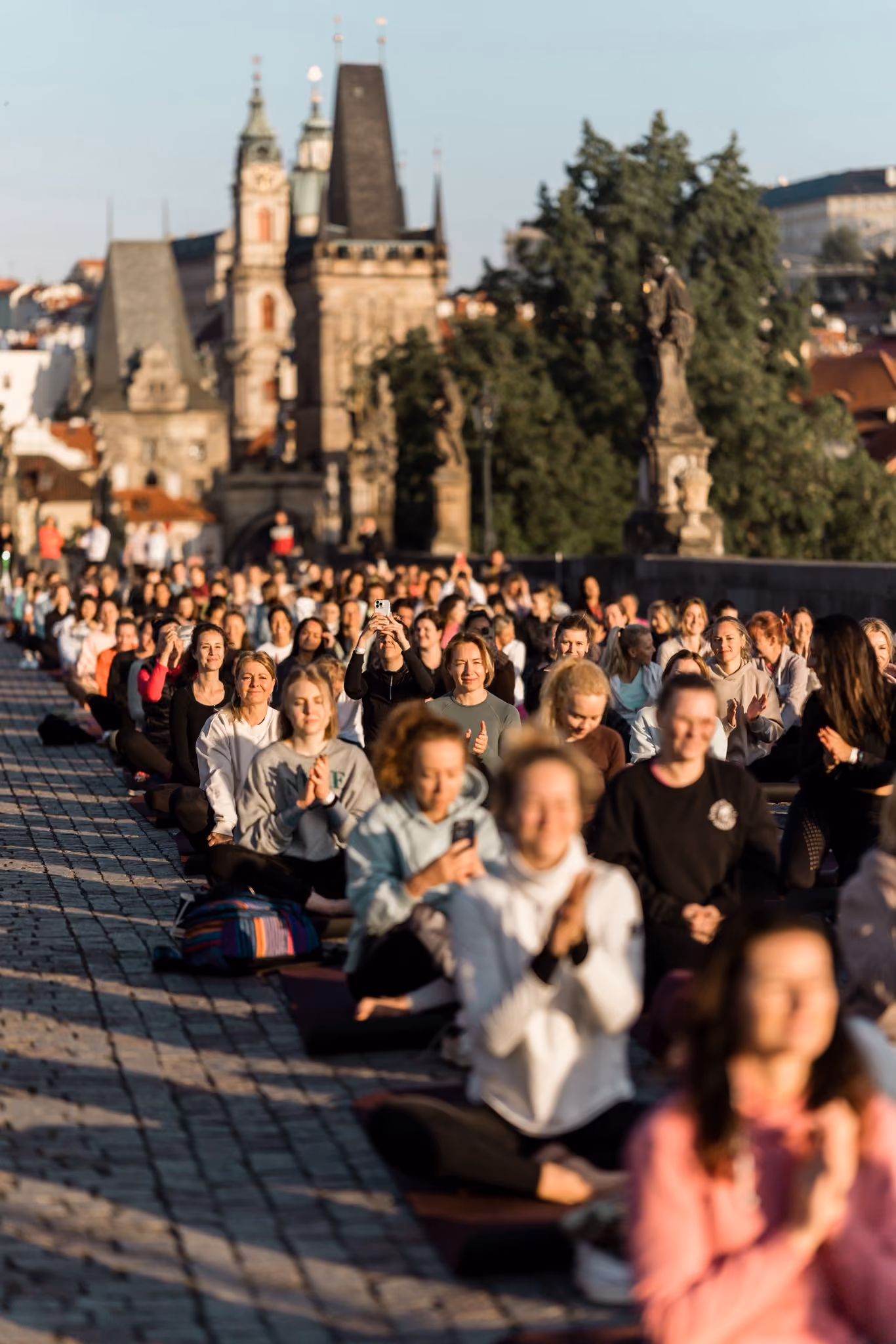 Stovky lidí cvičí na podložkách na Karlově mostě v Praze během ranního eventu Yoga Movement Experience.
