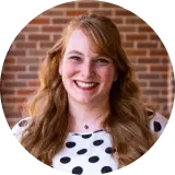 TeachFront testimonial headshot of Dr. Stephanie Valentine, smiling in front of a brick wall and wearing a black-and-white polka dot top.