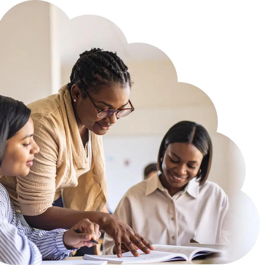 TeachFront hero image of an instructor guiding two students over an open book, symbolizing collaborative learning and supportive teaching.