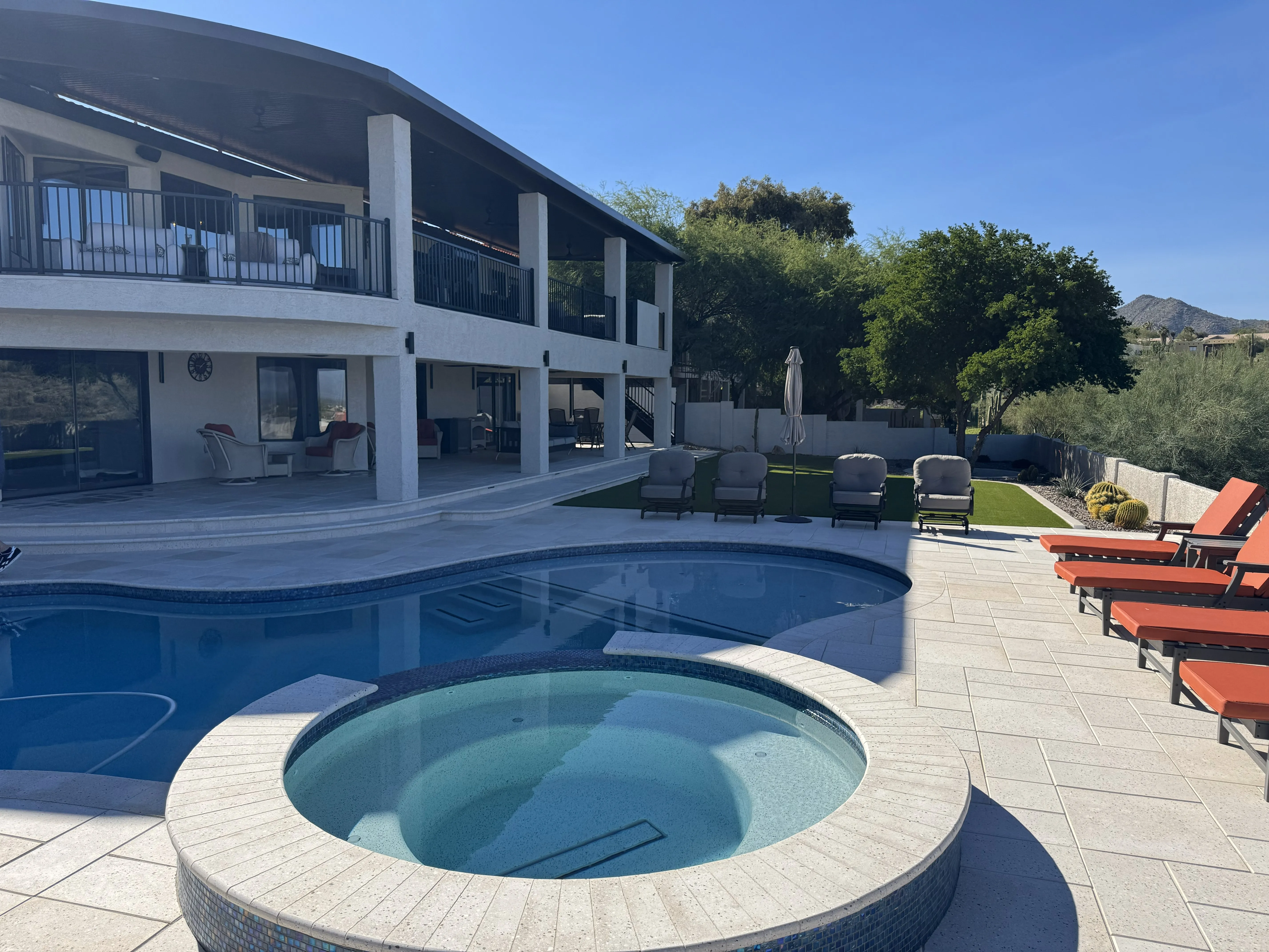 Completed luxury backyard reconstruction in Fountain Hills featuring a modern geometric pool, new integrated spa, structural multi-level patio rebuild, and professional site re-engineering for a seamless indoor-outdoor desert resort flow.