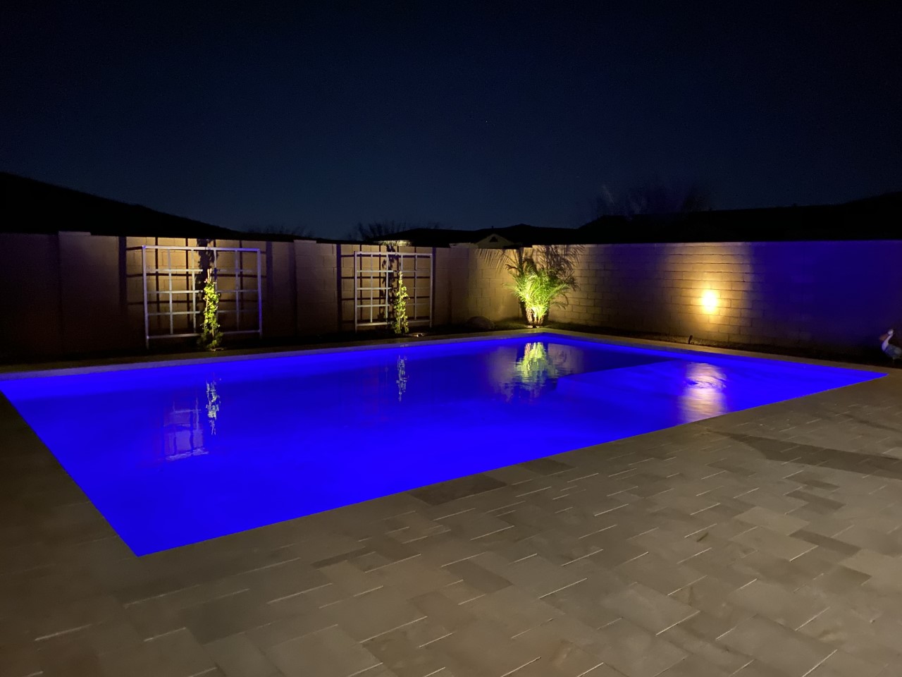 Luxury pool remodel in Chandler featuring vibrant blue LED lighting, automated modern design, and custom desert landscaping