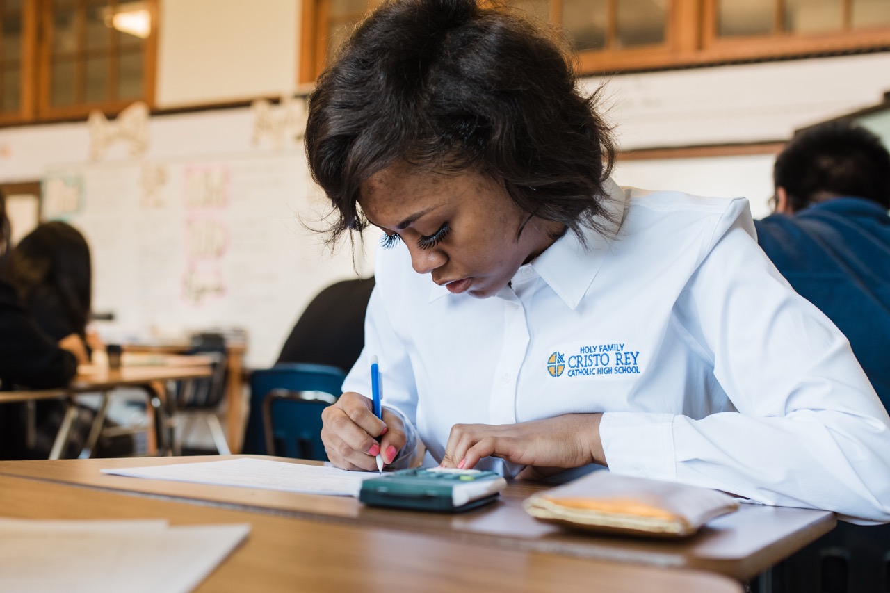 A Holy Family Cristo Rey student works on a math problem during class