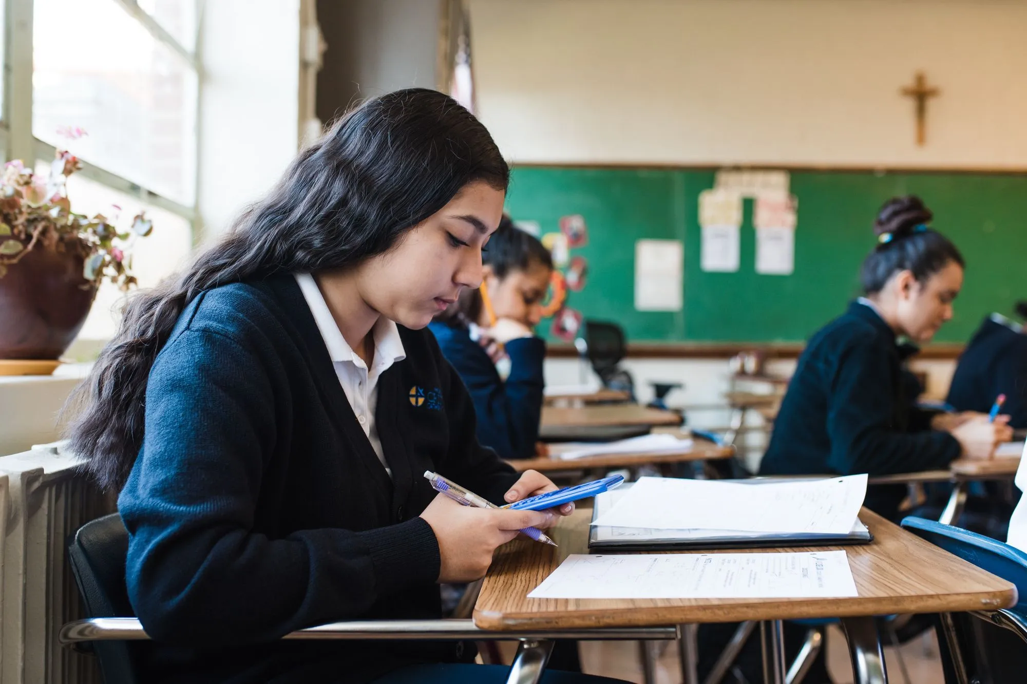 A young Hispanic woman uses a calculator during math class at Holy Family Cristo Rey Catholic High School