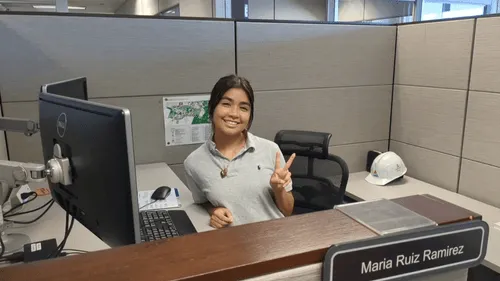 Holy Family Cristo Rey student Maria Ruiz Ramirez smiles and shares a peace sign at her Corporate Work Study job