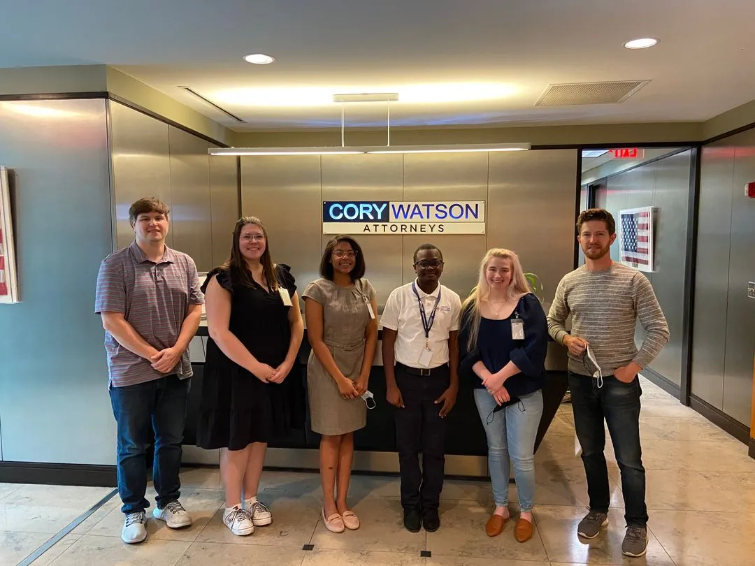 A Holy Family Cristo Rey student poses with his Corporate Work Study job supervisor and coworkers at Cory Watson Attorneys