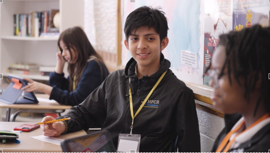 Students smile and work on classwork at Holy Family Cristo Rey Catholic High School