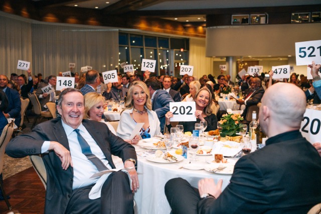 Guests at the 2025 Rey of Hope Gala hold up their bid numbers during the live auction