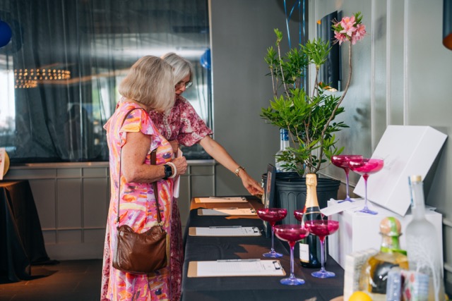 Two guests at the 2025 Rey of Hope Gala look over silent auction items during cocktail hour