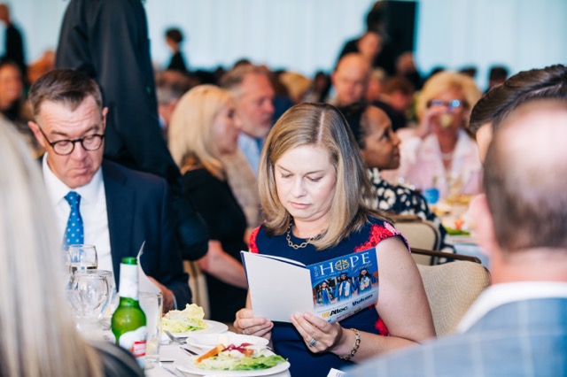 A guest at the 2025 Rey of Hope Gala reads the event program during dinner