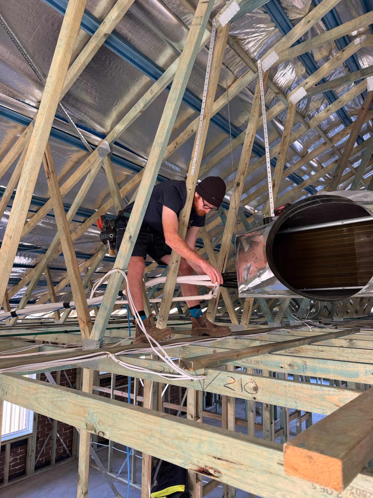 A man in a roof installing an air conditioner