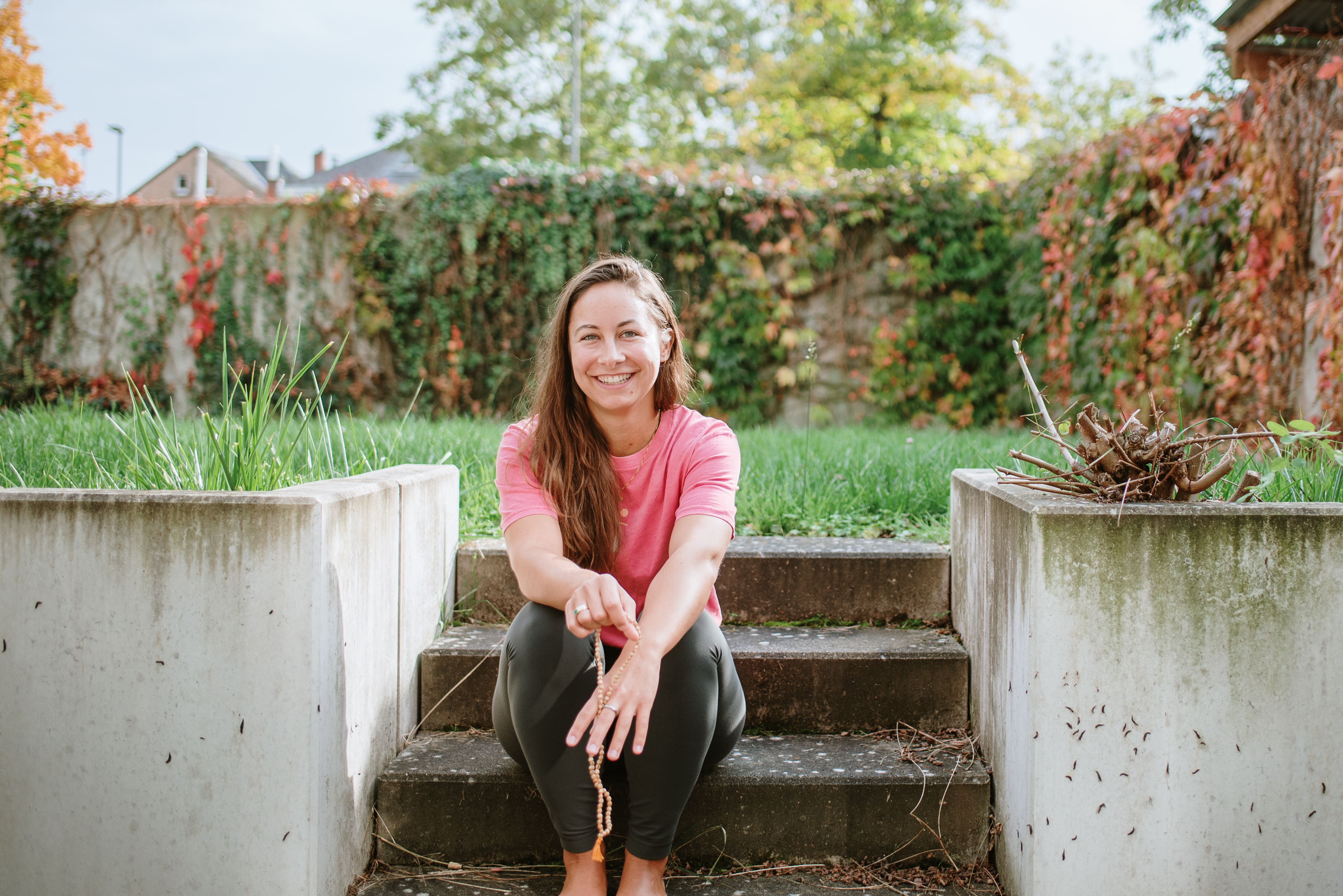 Die Besitzerin von Studio 42 sitzt auf einer Treppe und hält Mala-Perlen in ihren Händen
