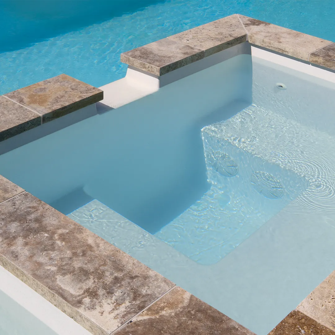 Close-up of a Peninsula spa pool with clear water and a tiled edge in beige tones.