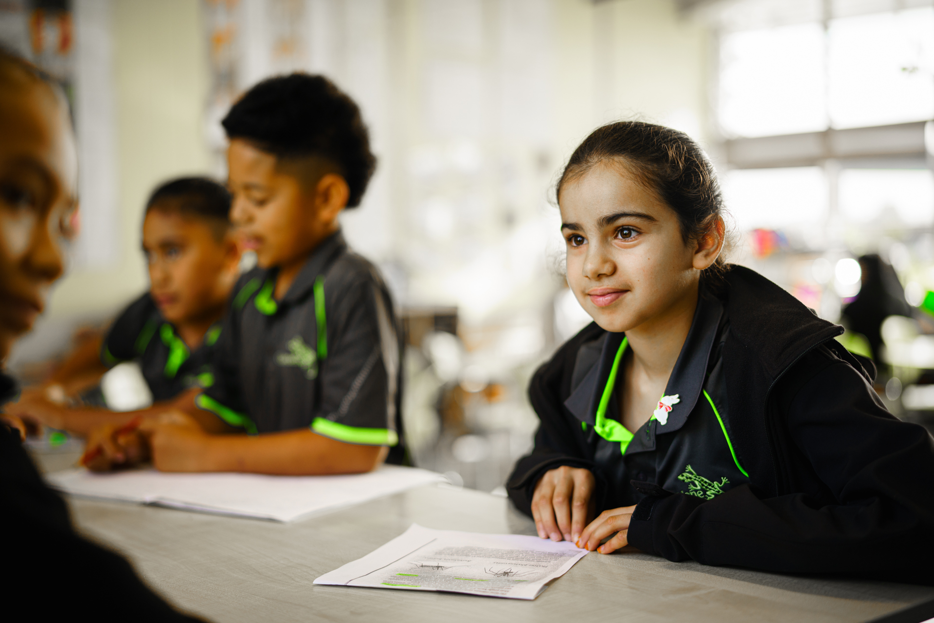 Young student smiles at her desk.