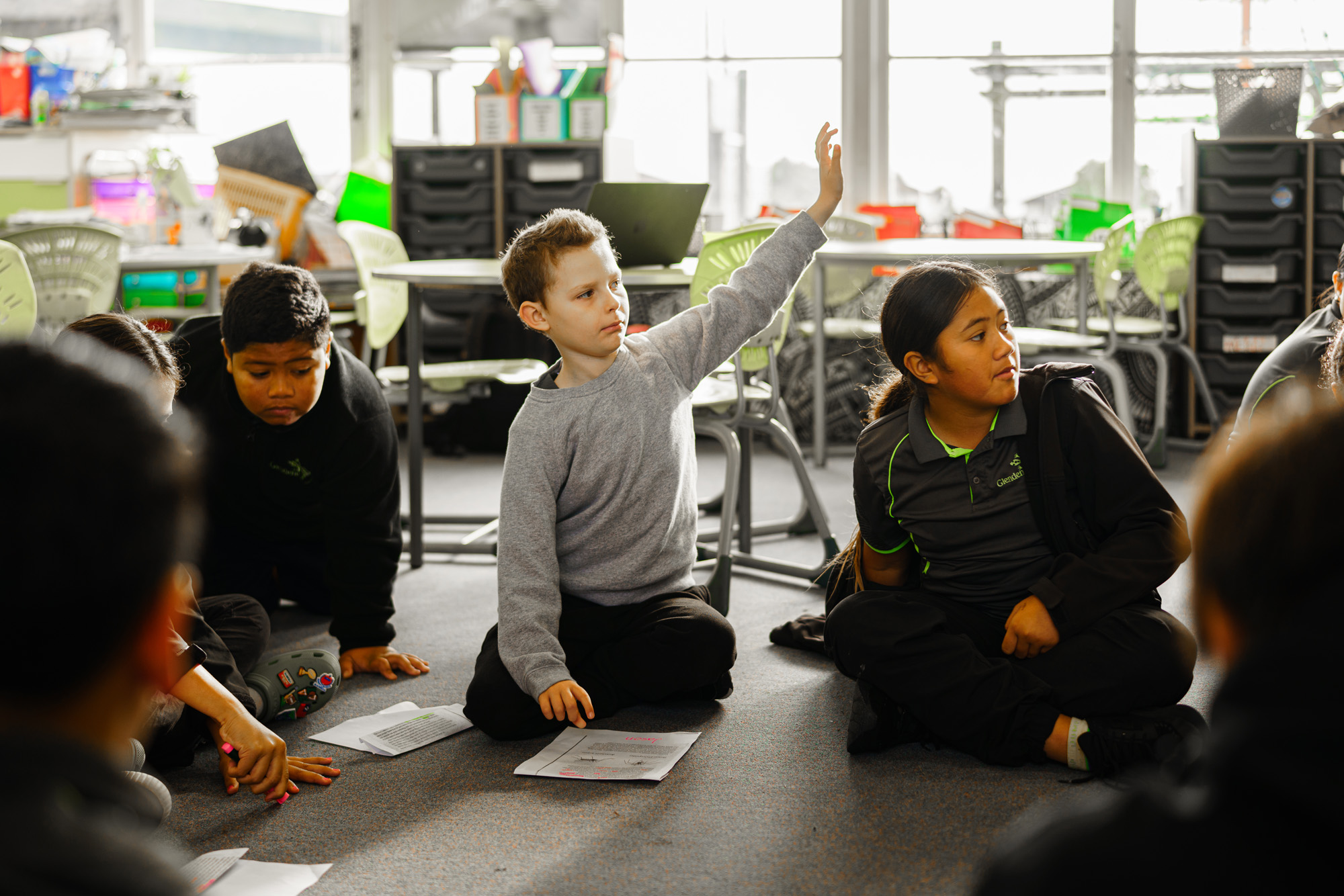Young student raises their hand in a classroom.