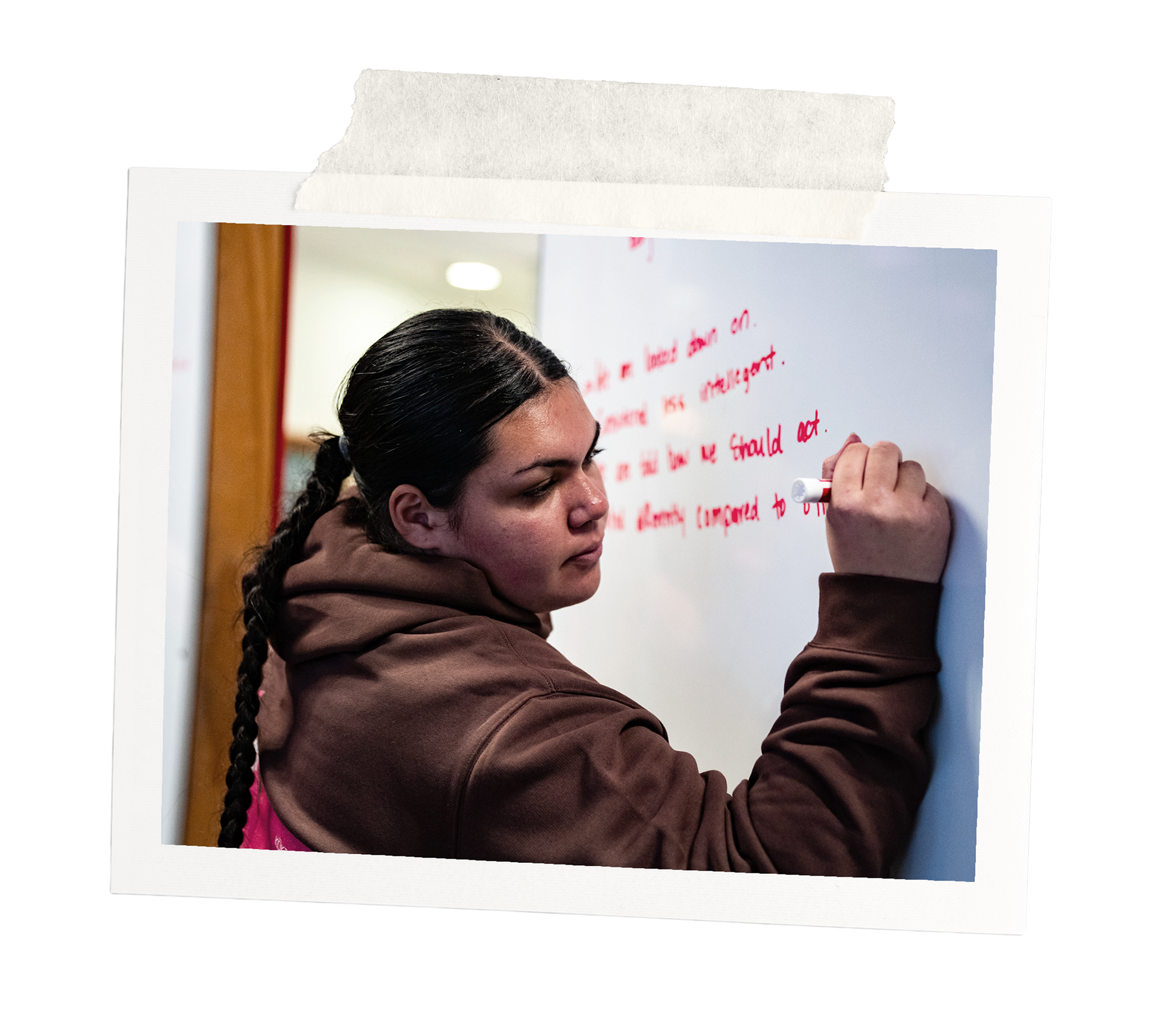 Young woman writes on a whiteboard at a Kōkirihia workshop.