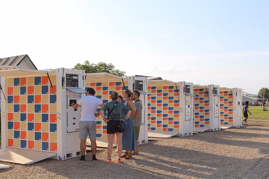A row of mobile outdoors lockers for an event and some people using them