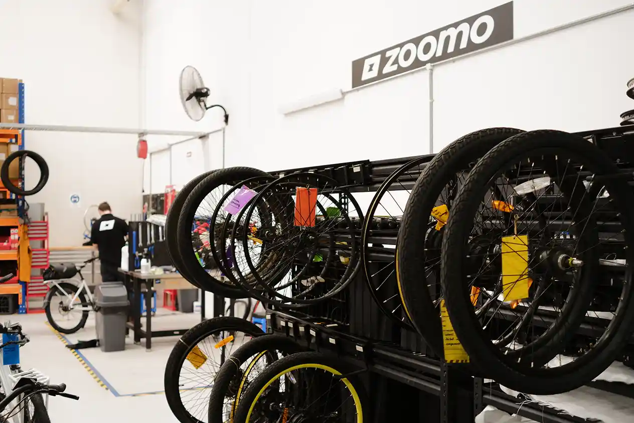 A workshop with Zoomo e-bikes and a person working, with the heading "Maintenance."