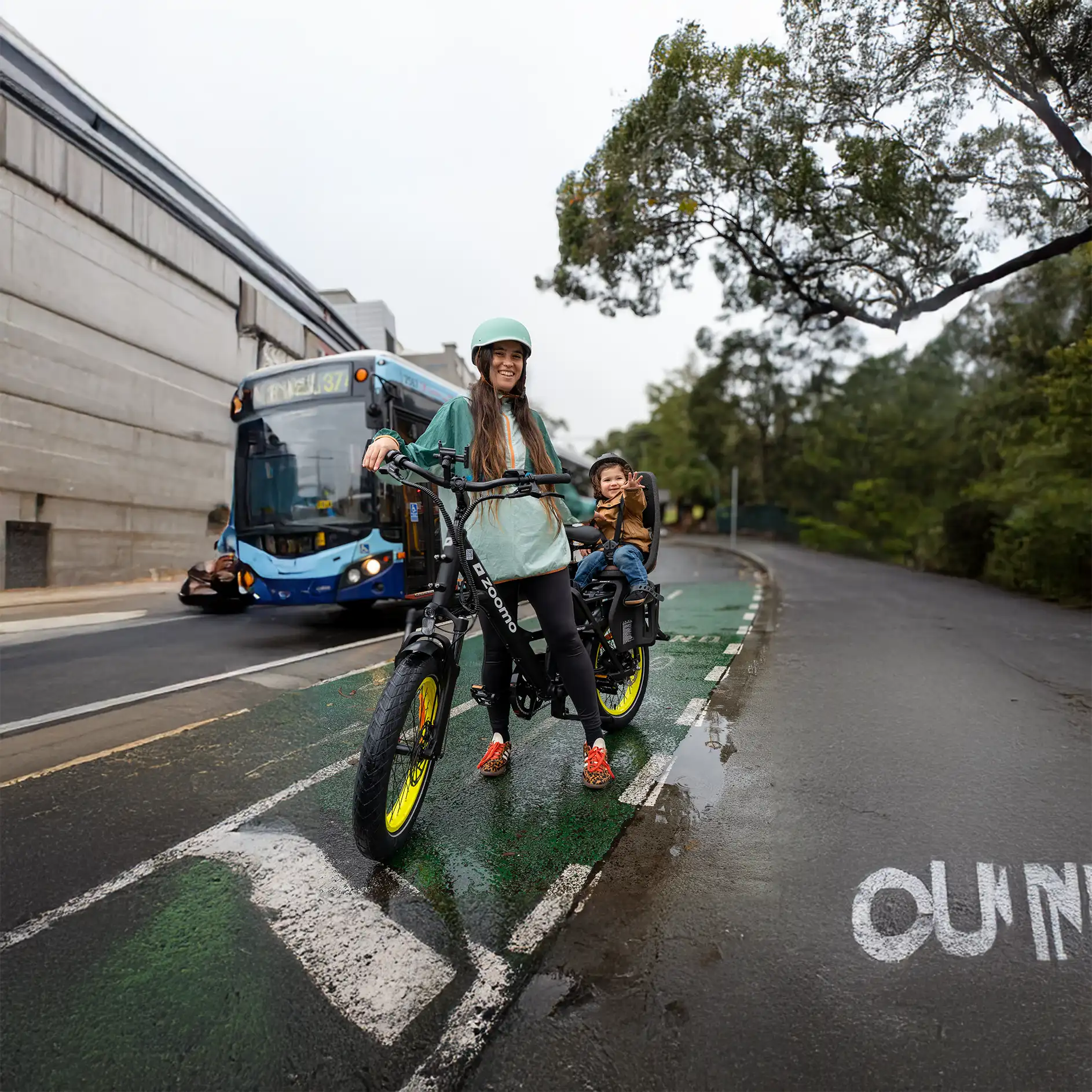 A parent and child riding a Zoomo Family e-bike on a city bike path.