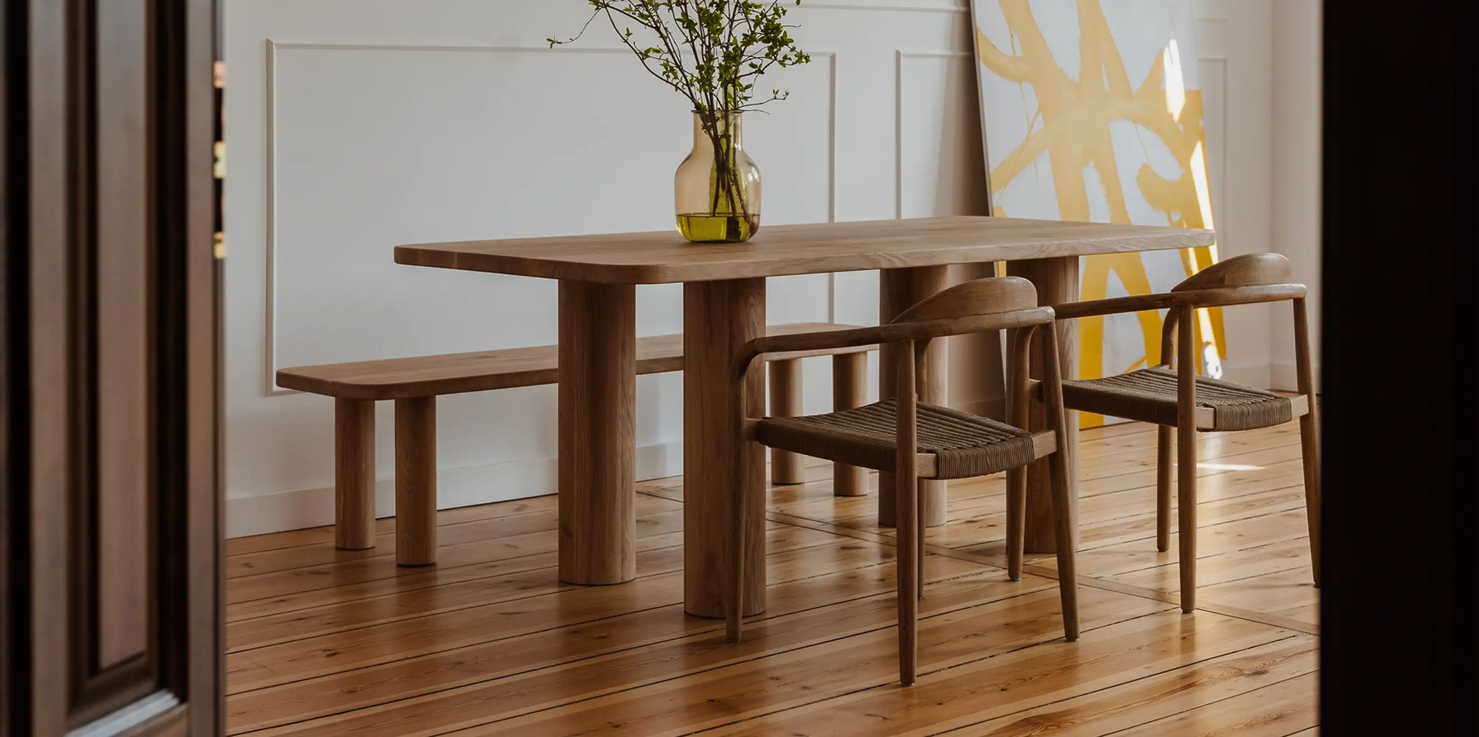 Dębowy stół z prostym blatem z zaoblonymi krawędziami i czterema masywnymi nogami w formie drewnianych walców.