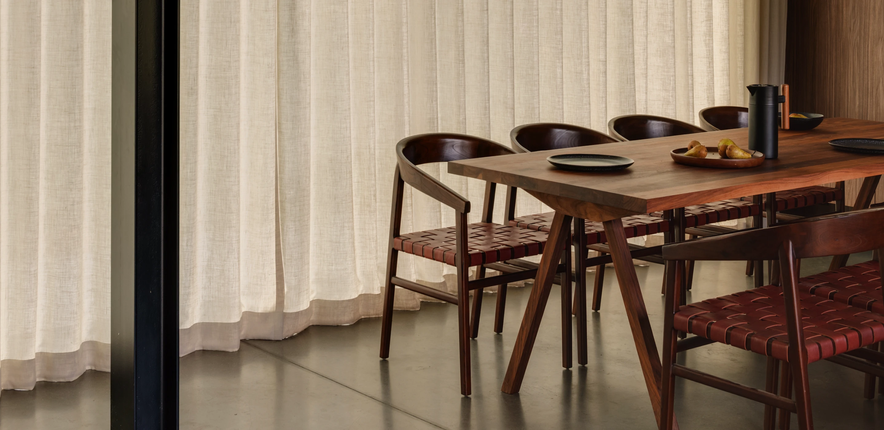 Drewniany nowoczesny stół jadalniany, z orzecha amerykańskiego z ciemnymi krzesłami z plecionymi siedziskami.