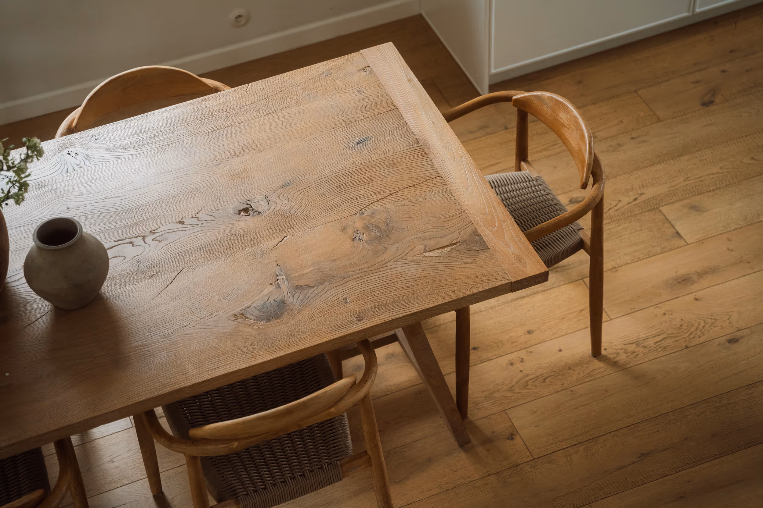 Stół rustykalny z naturalnego drewna z trzema drewnianymi krzesłami na tle drewnianej podłogi.