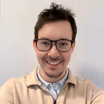 Mann mit Brille und hellem Hemd lächelt in die Kamera, Portraitfoto.