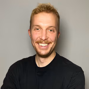 Mann mit schwarzem Shirt lächelt in die Kamera, Portraitfoto.