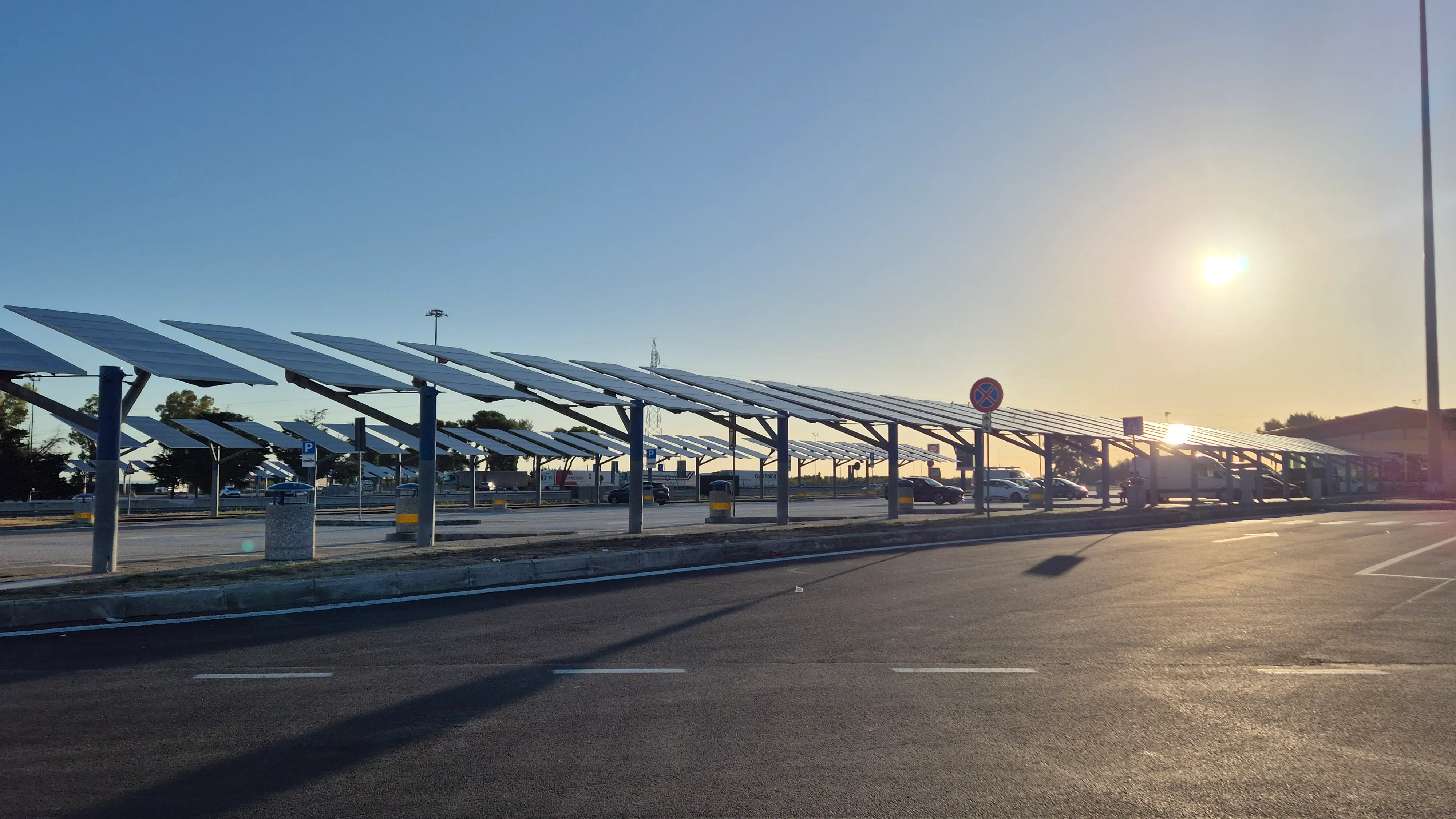 Parkplatz mit überdachten Solarpanelen bei Sonnenuntergang.