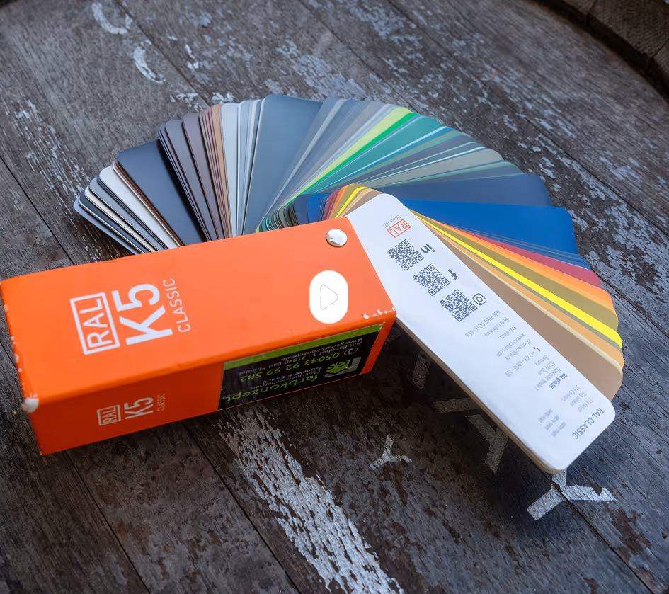 Farbfächer mit RAL K5 Classic Farbmustern auf einer dunklen Holzoberfläche.