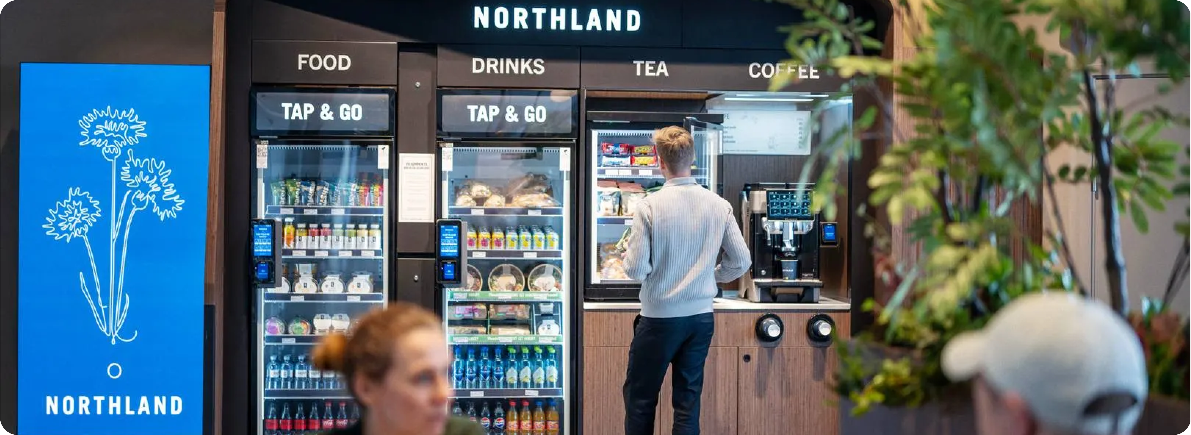 An image of a person ordering something at a vending machine using the payment terminals installed on the machine.