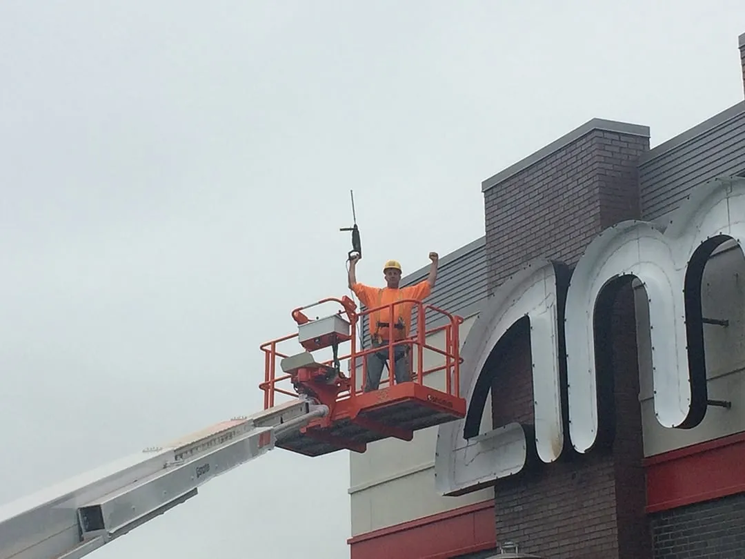 Martino Signs worker on lift installing exterior signs on Philadelphia building