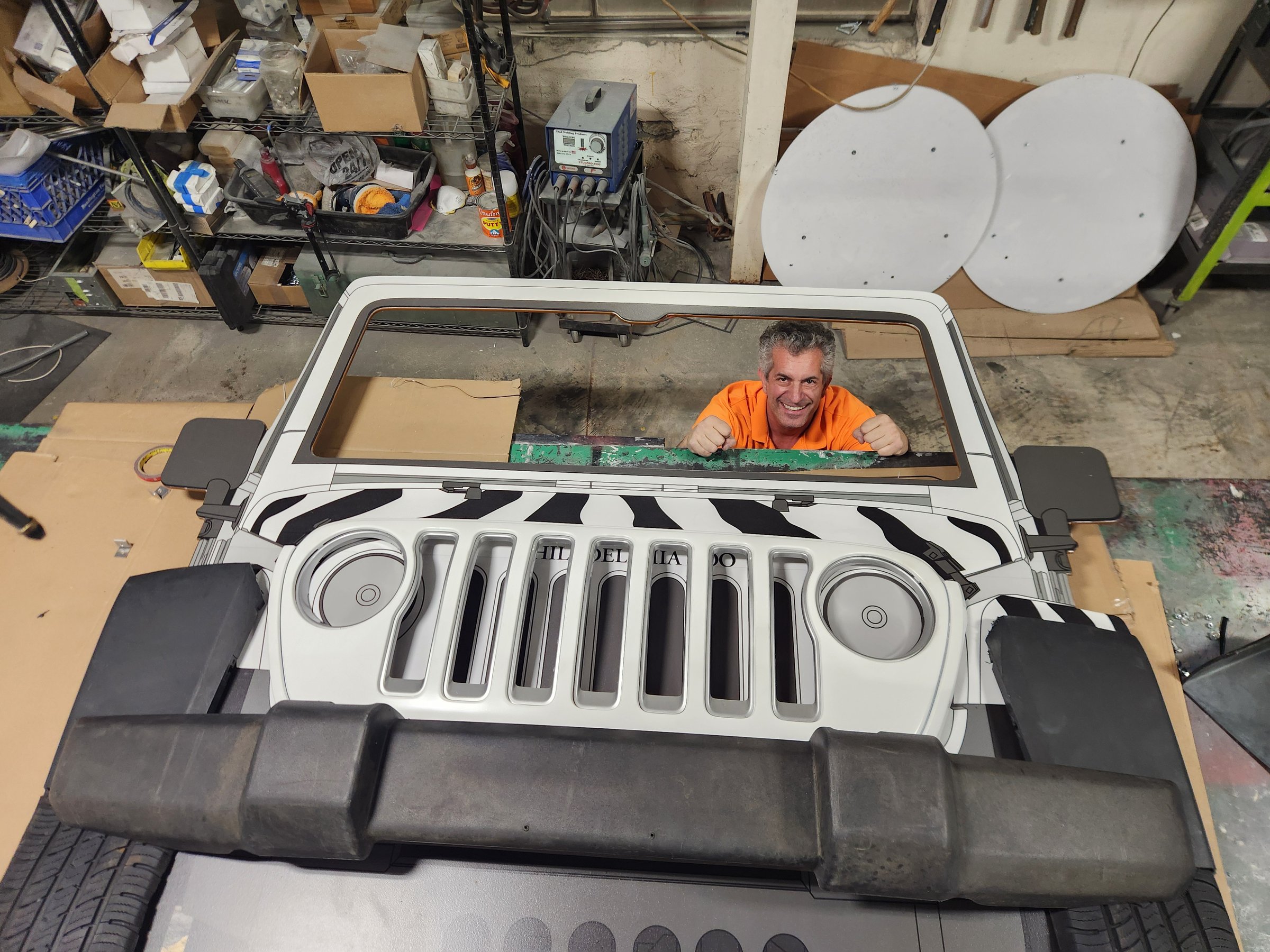 Crew member looking through the Jeep windshield over the zebra hood in the shop