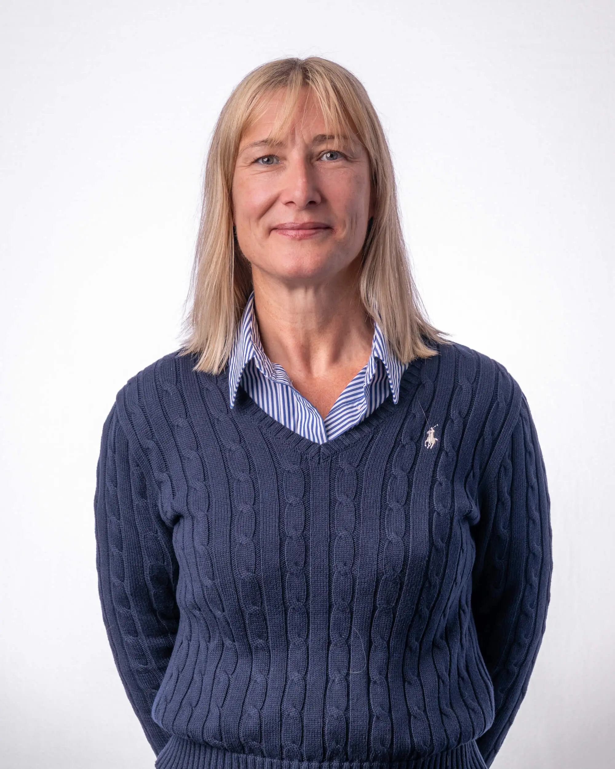 Introducing Alison Farrell our CFO a smiling middle-aged woman with blonde hair wearing a blue cable-knit sweater over a striped collared shirt, standing against a white background.