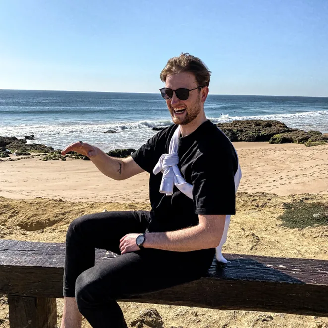 Person sitting on driftwood at scenic beach