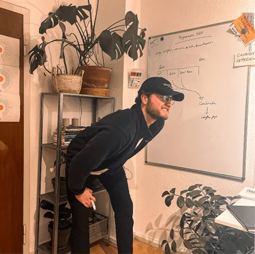 Person in casual attire standing besides whiteboard